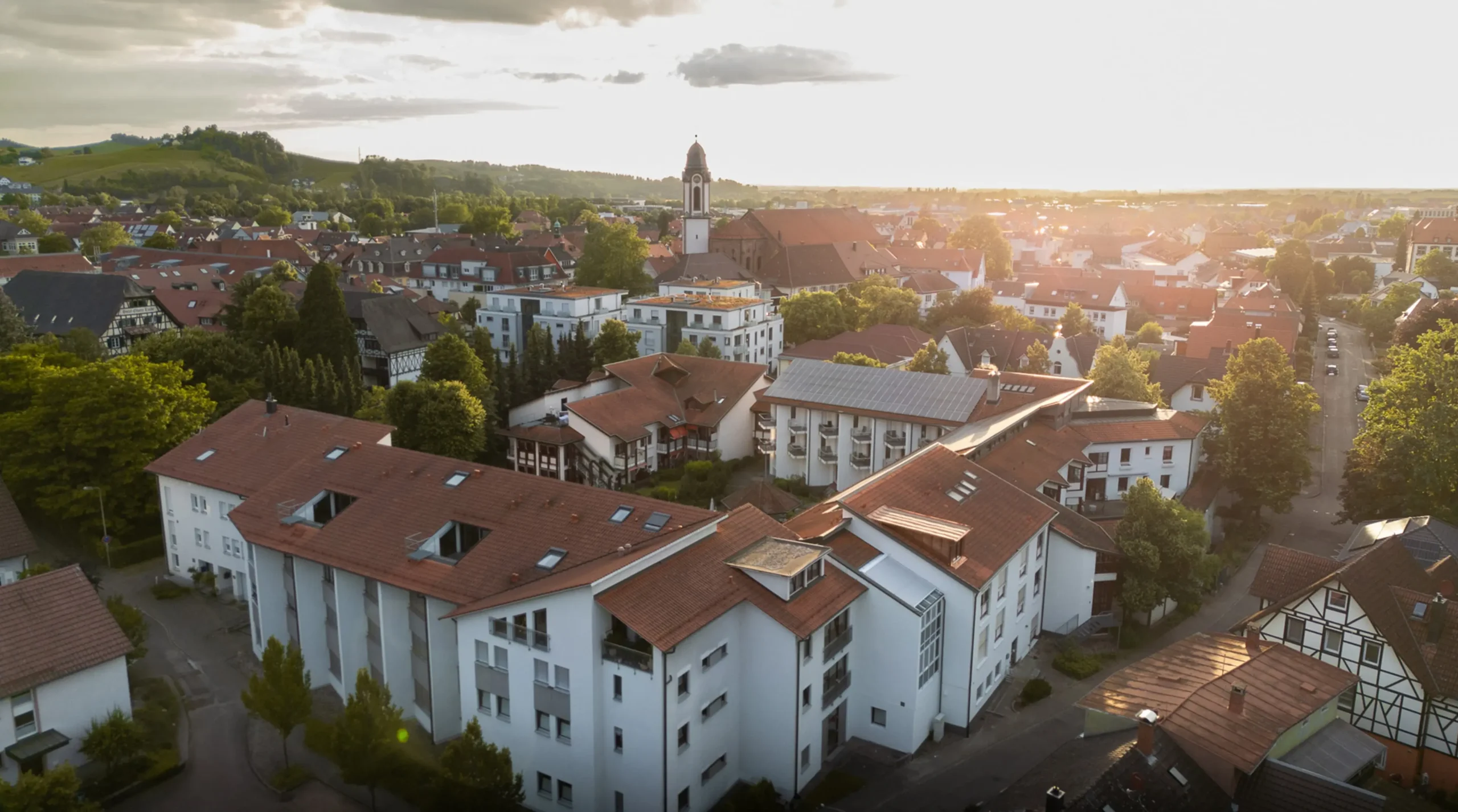 Luftaufnahme des Altenpflegeheims Wohnen & Pflege in Oberkirch. Das Bild wurde bei Sonnenuntergang aufgenommen und zeigt die umliegenden Gebäude sowie die malerische Landschaft. Teil von einem Imagefilm von Arisevision